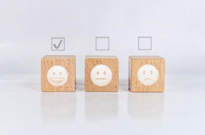 Wooden blocks with emoticon faces on and checkboxes above them