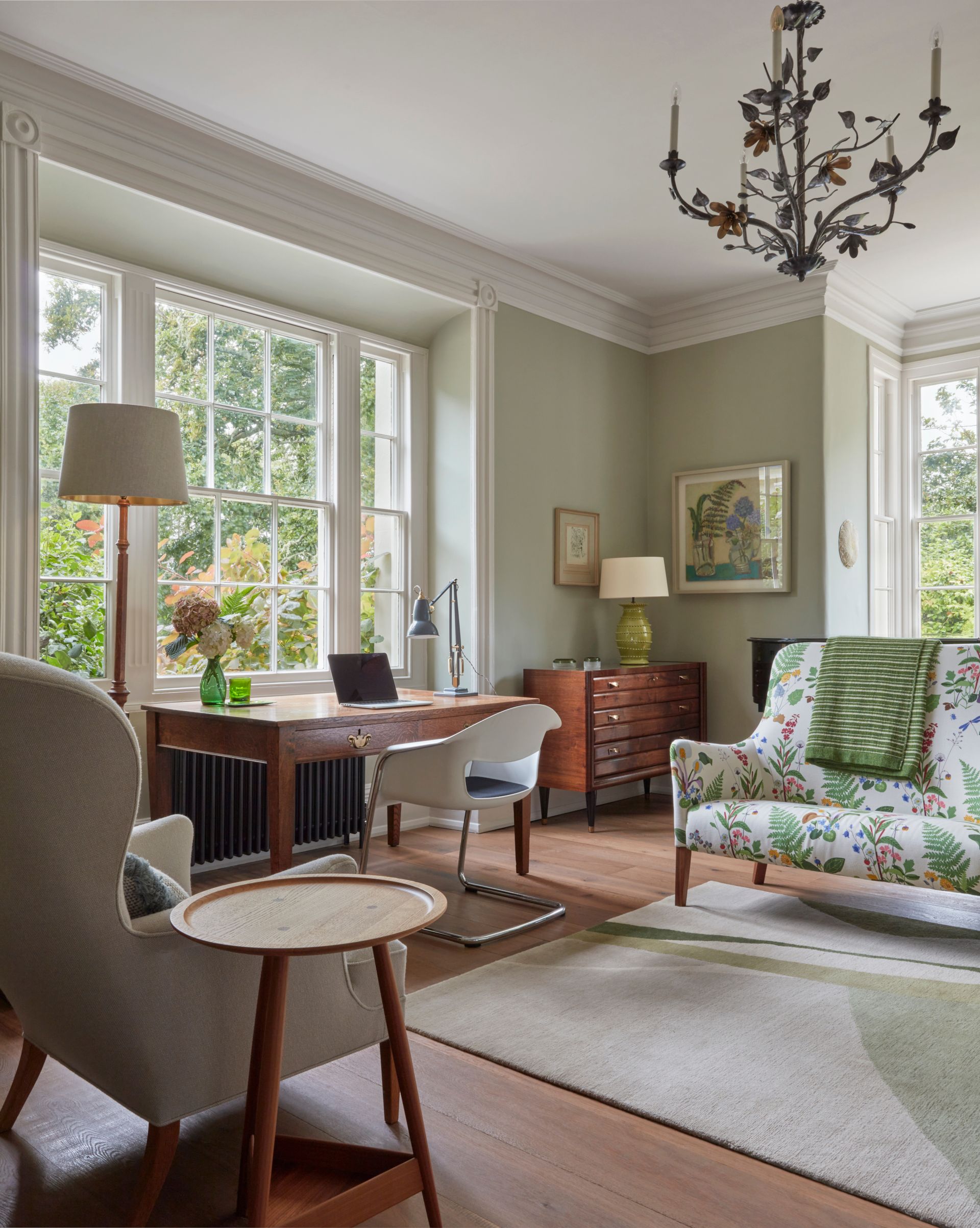 Living room with couch and armchair, desk and rug and netural walls