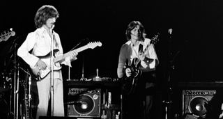 George Harrison and Robben Ford perform live in 1974. Here, Harrison plays his Fender Stratocaster, while Ford is on a semi-hollow electric guitar.