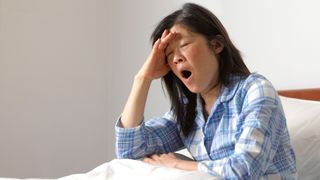 Woman sitting up in bed yawning