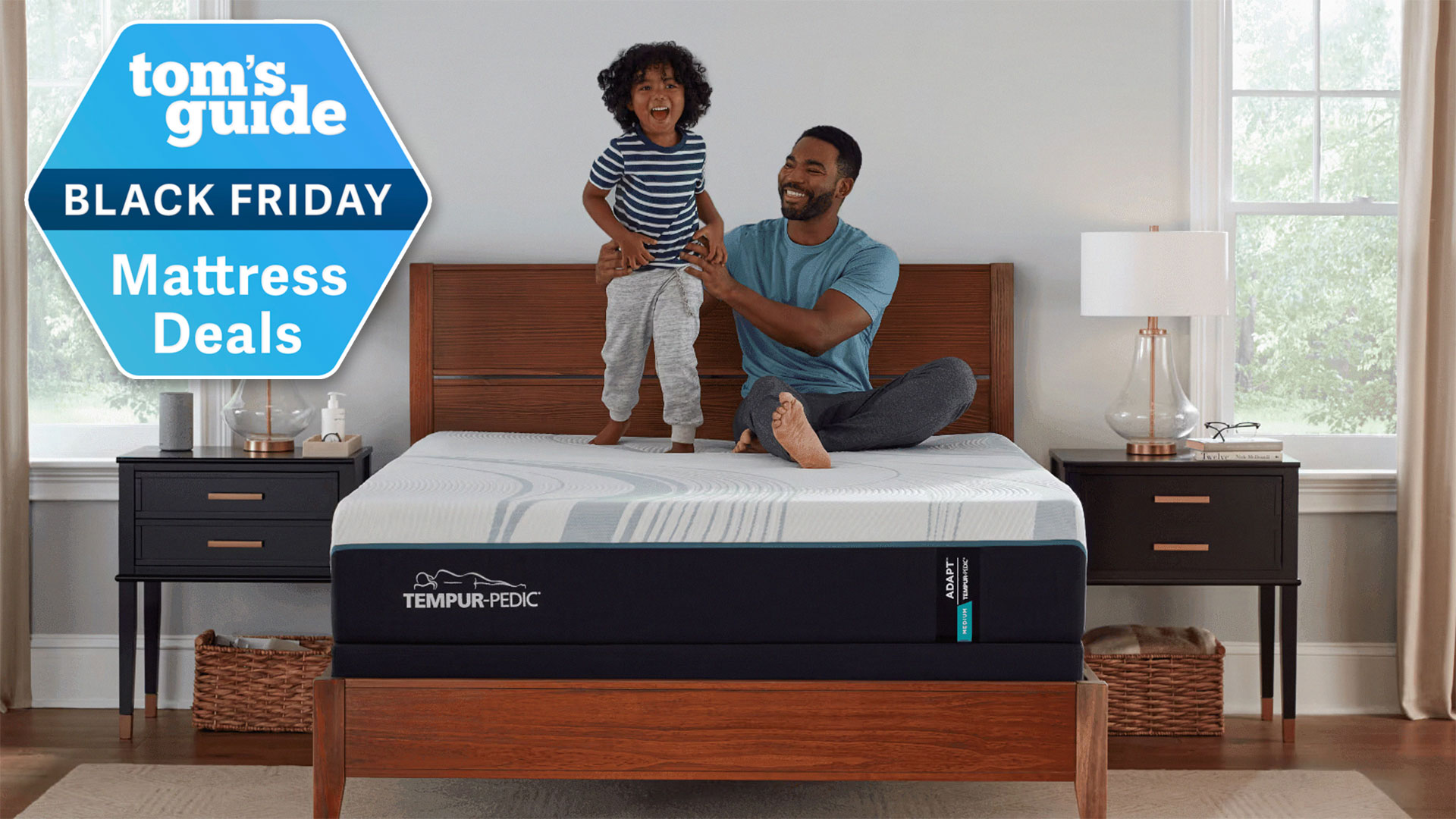 A father and child on a Tempur-Adapt mattress in a bedroom, with a Tom&#039;s Guide Black Friday Mattress Deals badge overlaid
