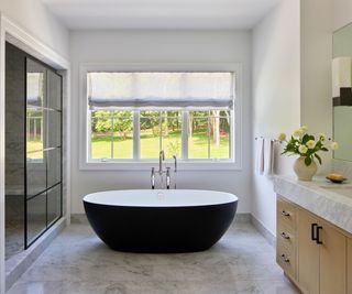 bathroom with black tub in window and marble floor