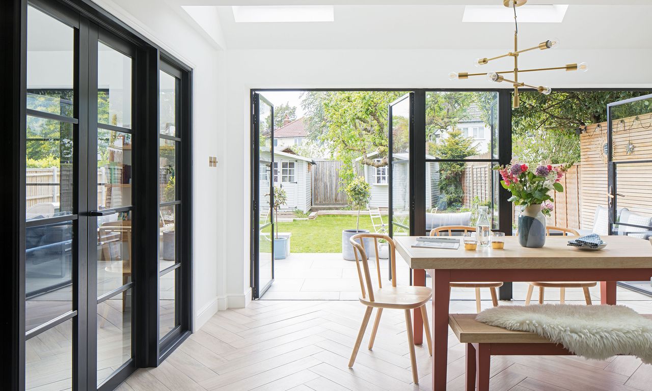 Open plan dining space with crittal-style doors opening to a garden