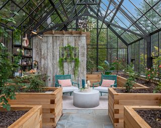 A large greenhouse with sitting area and raised garden beds