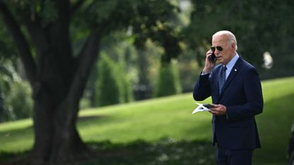 President Joe Biden talks on the phone outside the White House 