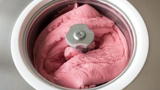 An ice cream maker bowl with pink ice cream inside