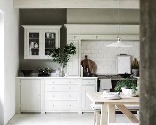 A white kitchen with pale wooden bench and pendant light