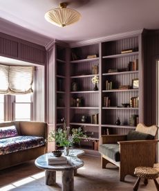 Living corner with open styled shelving and sofa and armchair around coffee table