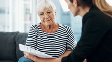 An older woman discusses paperwork with a financial adviser.