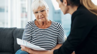 An older woman discusses paperwork with a financial adviser.