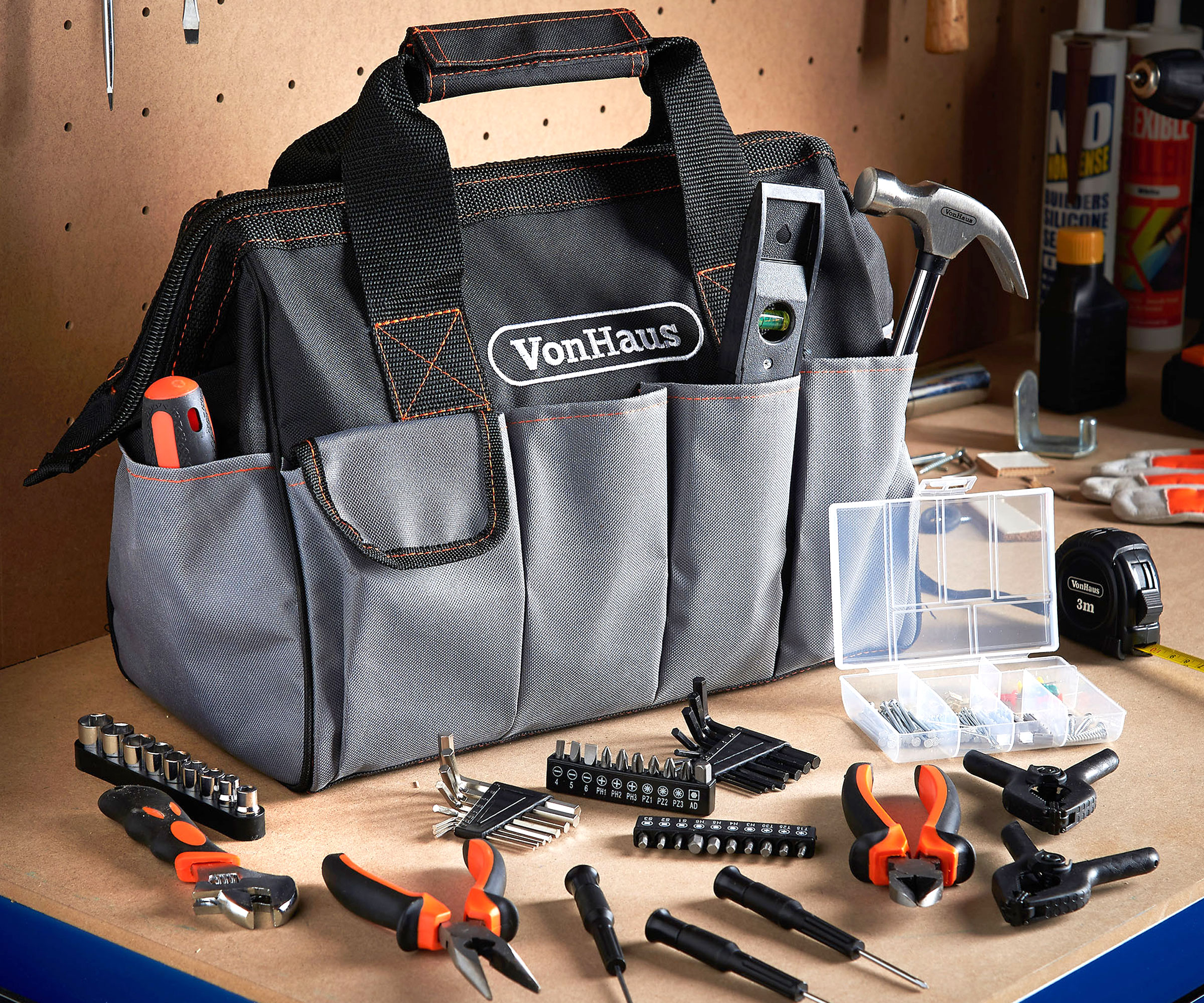 Black and grey canvas tool carry bag on wooden surface with tools laying around it