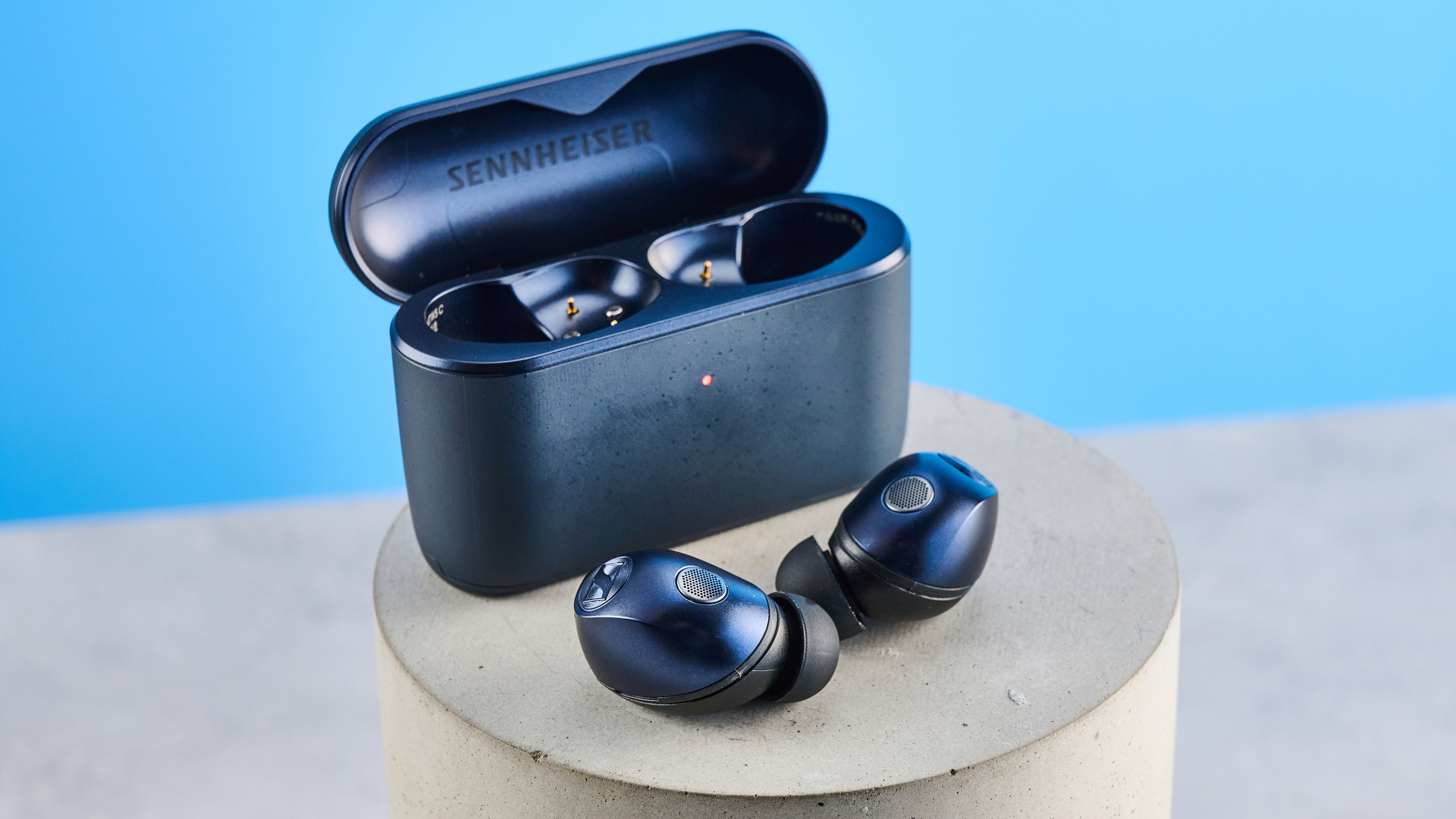 the sennheiser momentum 5 true wireless earbuds in navy photographed with the blue tom's guide background