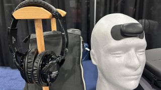 myWaves Pebble device on a styrofoam head beside a pair of headphones