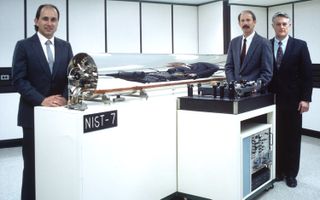 Researchers John P. Lowe, Robert E. Drullinger, and project leader, David J. Glaze (from left to right) stand next to a cesium atom clock they developed called NIST-7. Housed at the National Institute of Standards and Technology, this clock was responsible for keeping time in the U.S. from 1993 to 1999, but has since been replaced by more accurate cesium clocks.