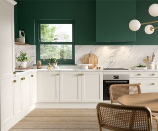 white shaker kitchen units with green painted walls and wooden floor