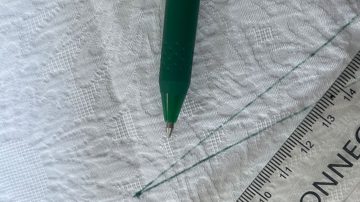 How to sew beginners; a close up of a pen on a fabric pattern