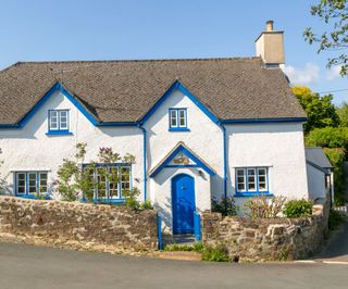 A white rendered cottage with bright blue detailing