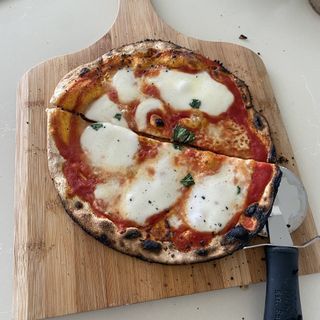 pizza Margherita on a chopping board with pizza slice