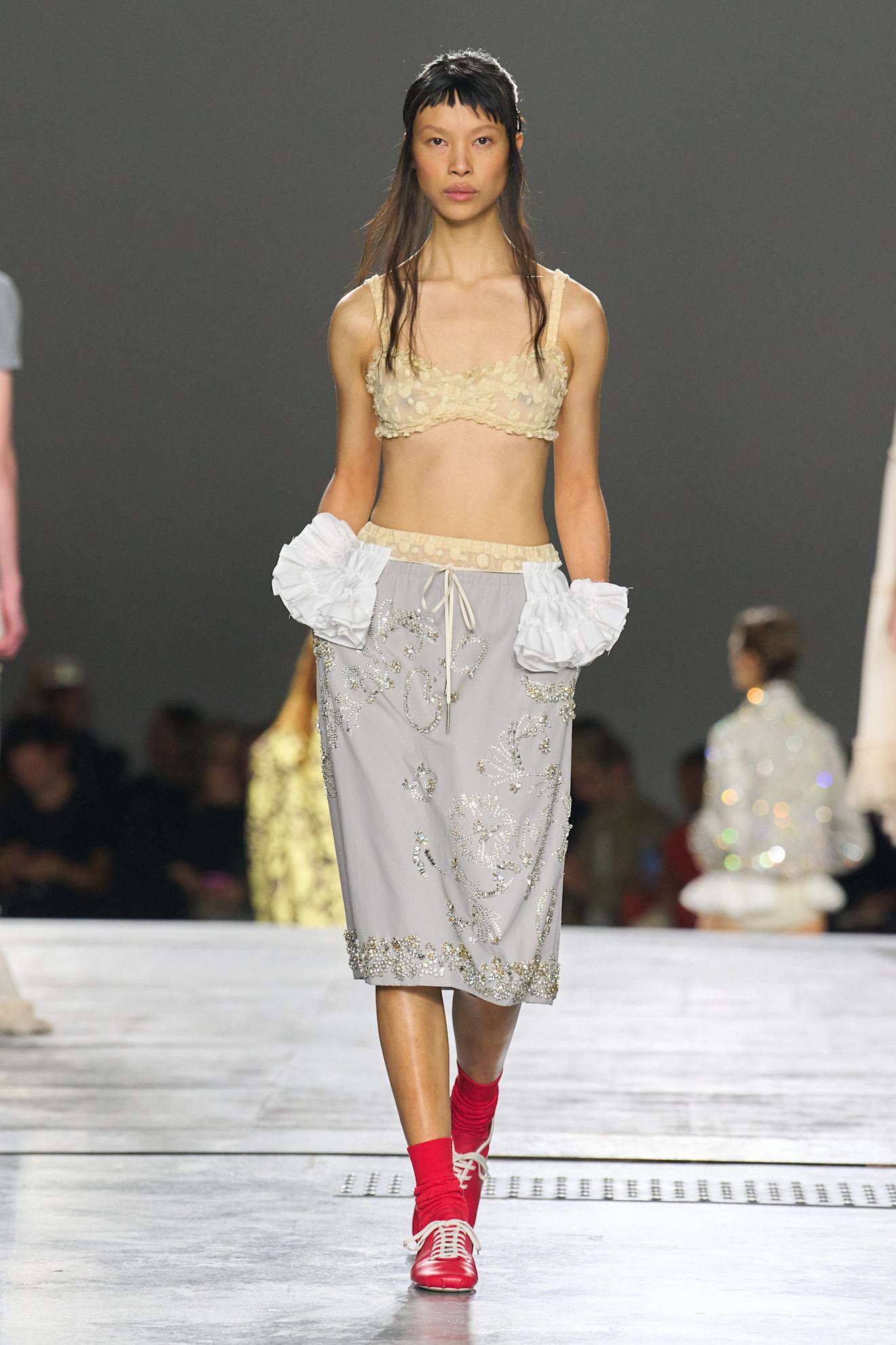 A model at the spring/summer 2026 Dries Van Noten show wearing a bra top and a bejeweled gray skirt.
