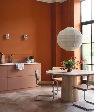 Orange kitchen with round dining table in foreground