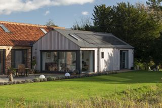 timber clad extension to brick barn with solar panels
