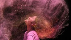 A woman tosses her hair in a cloud of coloured powder during the Hindu festival of Holi in Chennai, India