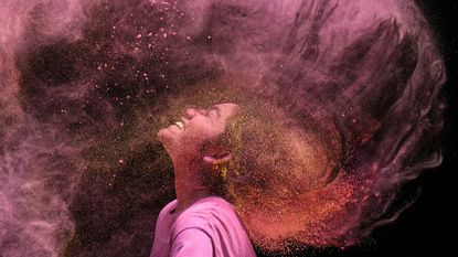 A woman tosses her hair in a cloud of coloured powder during the Hindu festival of Holi in Chennai, India