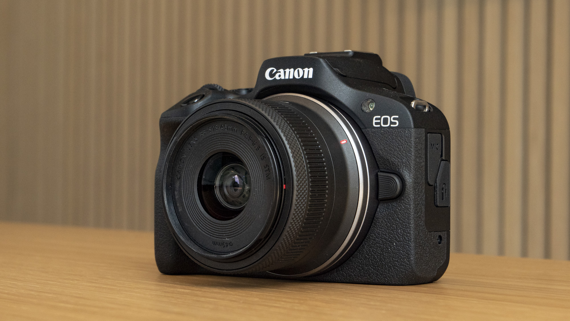 Canon EOS R100 camera on a table front angled