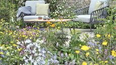 A colourful flower bed in front of a relaxed paved seating area