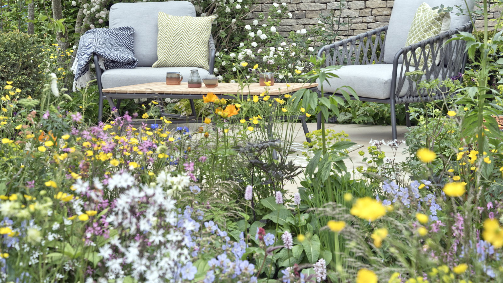 A colourful flower bed in front of a relaxed paved seating area