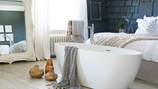 white freestanding bath at the end of a bed in a bedroom