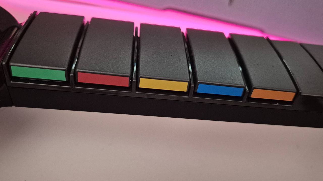 Photos of the Turtle Beach PDP Riffmaster guitar controller (PlayStation version) taken by writer Rosalie Newcombe, in a pink and white office.