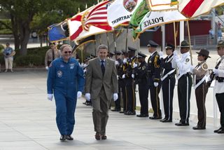 Kennedy Center Director Bob Cabana and Vehicle Integration Test Office and former NASA astronaut Jerry Ross walk past an honor guard at NASA's Kennedy Space Center Visitor Complex to participate in a U.S. Honor Flag presentation ceremony. The flag will be
