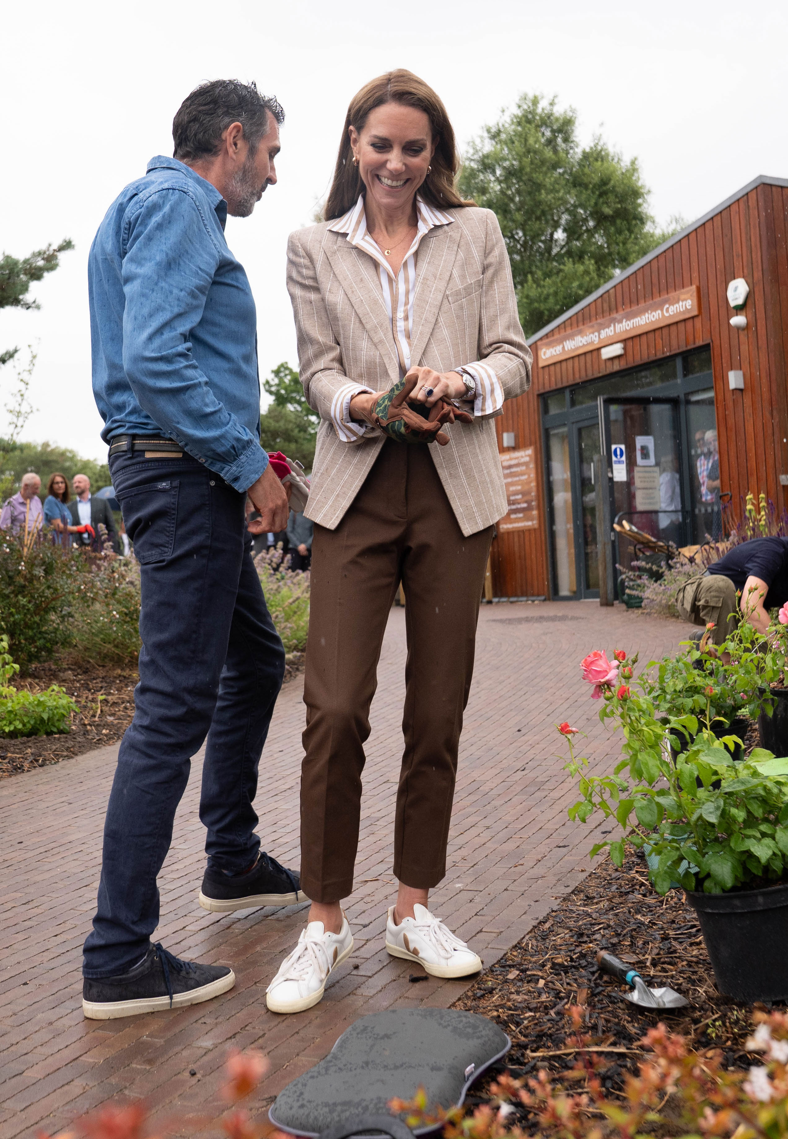 Kate Middleton wears a brown striped blazer with brown pants and white sneakers