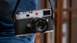 The Leica M11 camera hanging by its camera strap