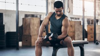 A man performing dumbbell bicep curls sat on a weight bench