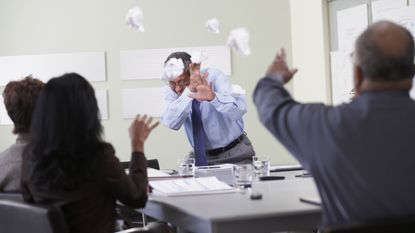 Employees throw wads of paper at their boss because of bad leadership.