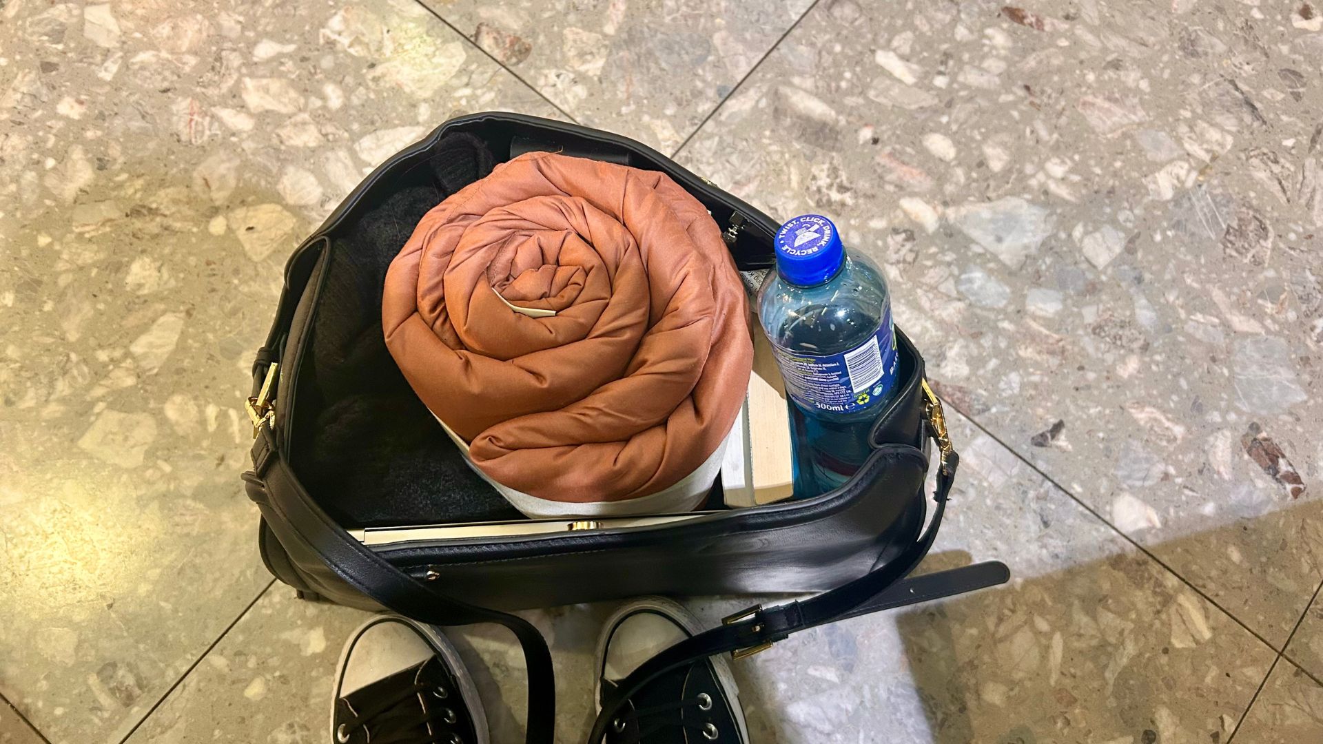 The Huzi Infinity Pillow in a carry-on handbag on the floor of London Heathrow Airport