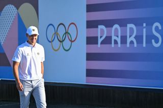 Matthias Schmid walks past an Olympic rings sign