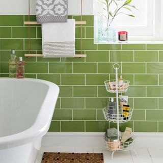 Wood towel ladder on tiled green bathroom wall with toiletries displayed in wire storage racks