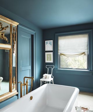 bathroom with teal color-drenched walls and ceiling, gold accents and white bath