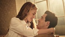 A young couple embraces in a sun-lit loft.