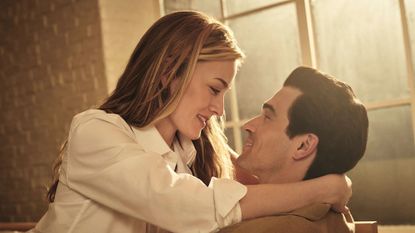 A young couple embraces in a sun-lit loft.