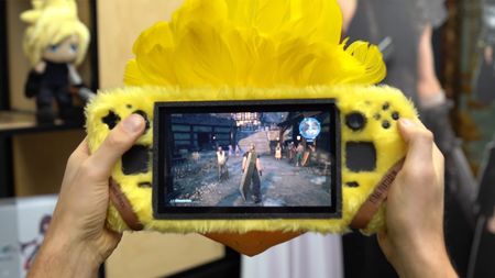 Two hands are seen playing Final Fantasy VII Rebirth on a custom Steam Deck. The handheld gaming PC is designed to look like the RPG series' fantastical giant birds, called Chocobos. The handheld gaming PC is covered in yellow fur, and has a crest of yellow feathers plus an orange beak either horizontal side of its screen.