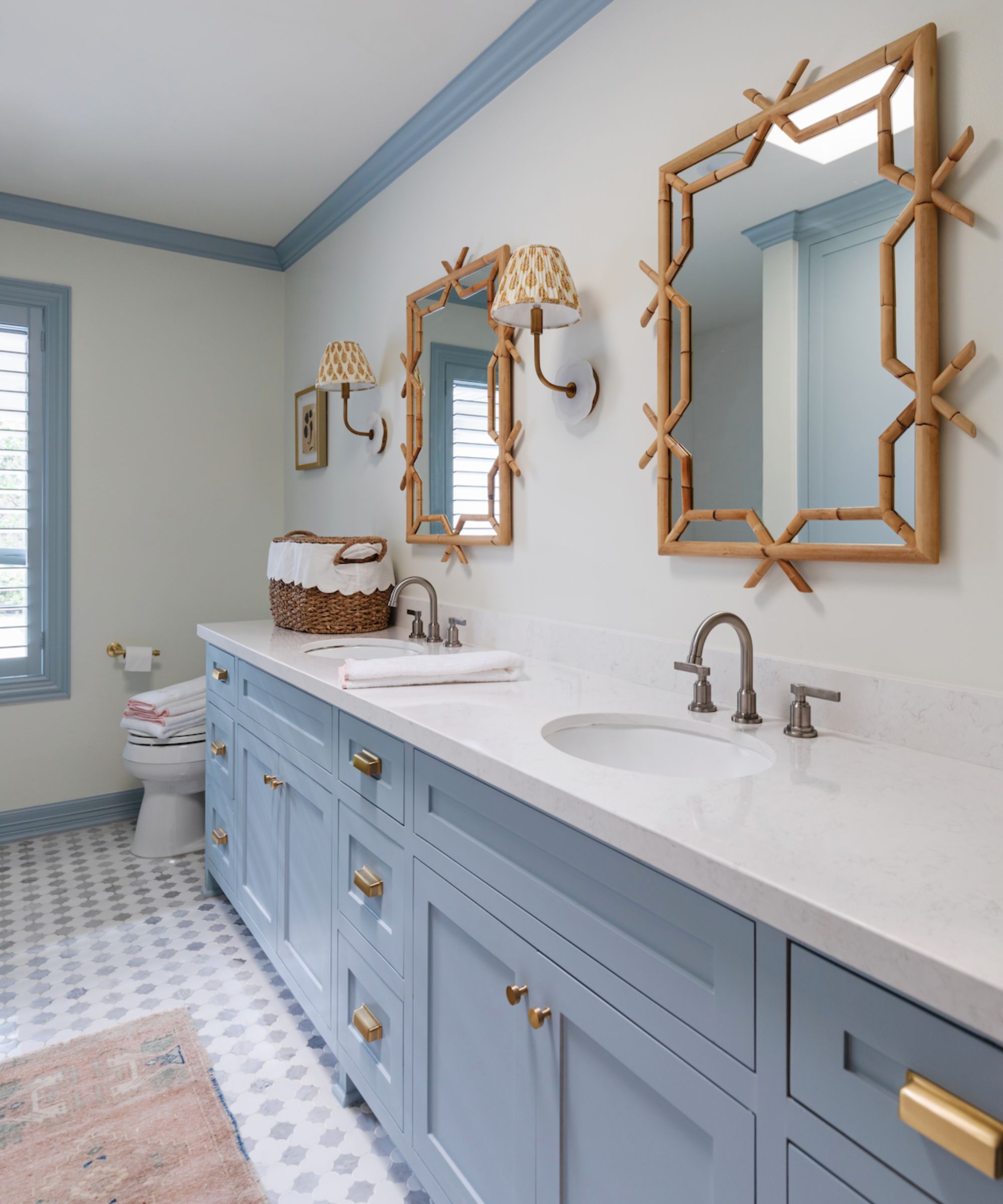 Bathroom with pale blue painted cabinetry andn and ceiling border, blue and white tiled floor and bamboo mirrors
