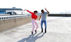 Teenagers dancing on a London rooftop overlooking the city. - stock photo