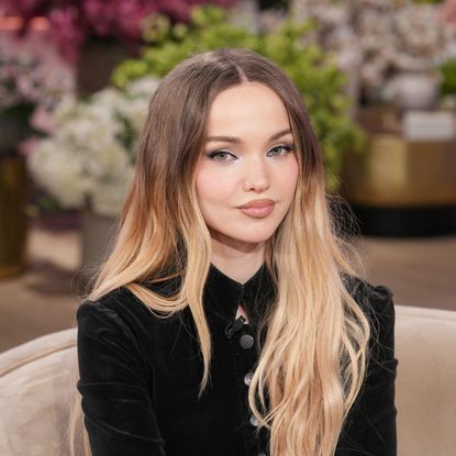 a white woman with dark roots and blonde ends posing on a set in front of a studio audience