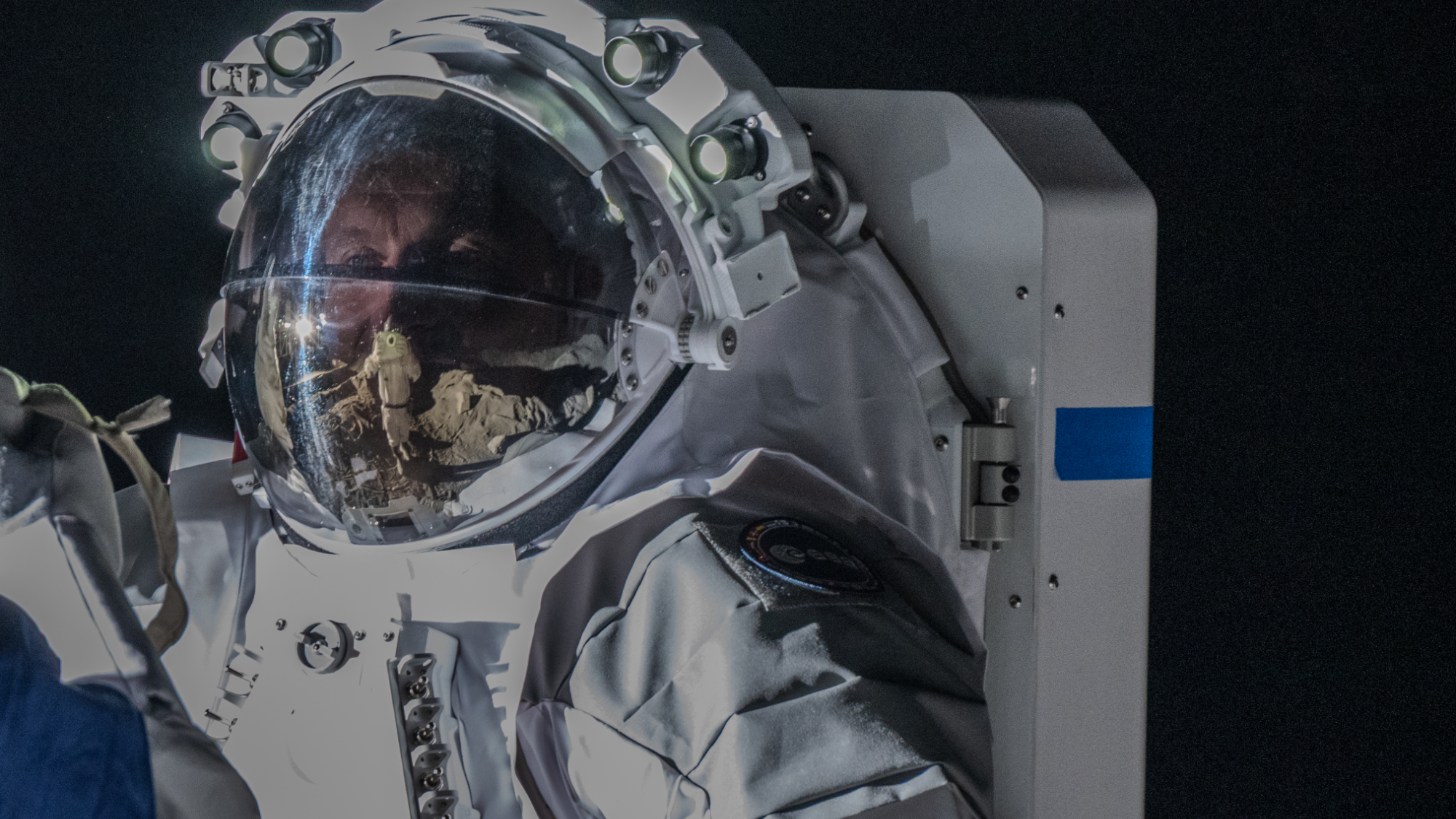 closeup of the helmet and upper torso of an astronaut in a white spacesuit during an exercise here on earth
