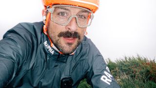 A man in an orange bike helmet in the rain