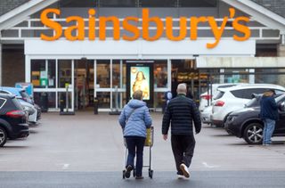 Customers push a shopping trolley towards a J Sainsbury Plc supermarket in Basildon, U.K., on Tuesday, Jan. 11, 2022